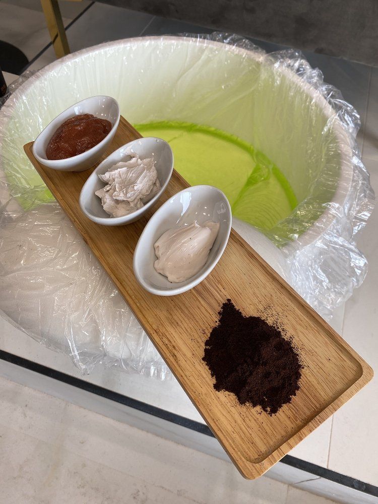 A pedicure tray of scrubs and masques over a jelly foot bath