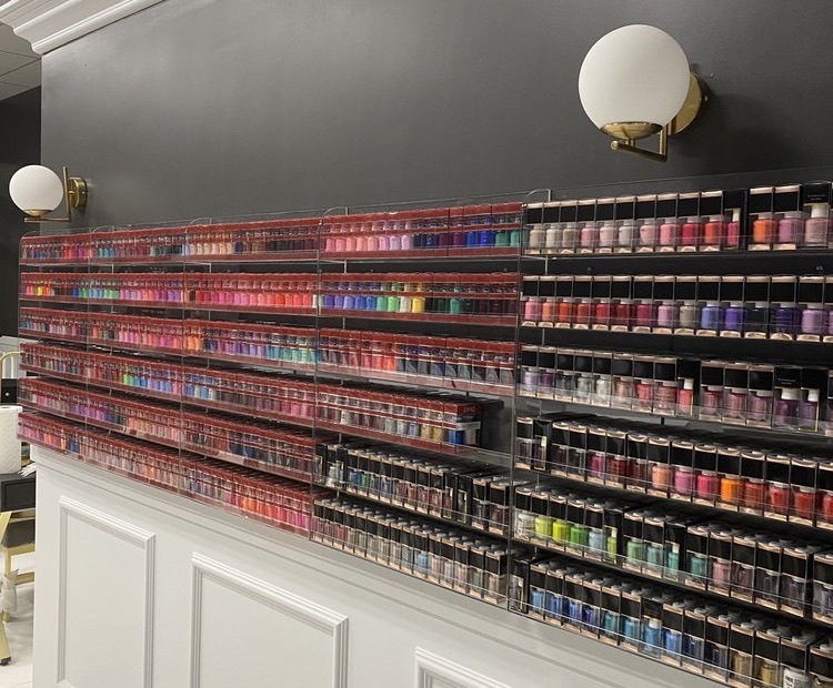 Our polish wall: hundreds of colors on the charcoal wall under brass globe lights